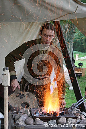 A Saxon using bellows to stoke up a fire at the reenactment of The Battle of Hastings in the UK Editorial Stock Photo