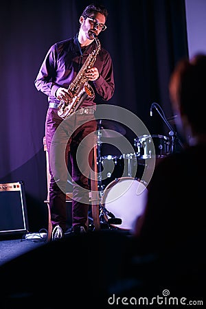 Saxophone player on stage. Silhouette of listener on a foreground Stock Photo