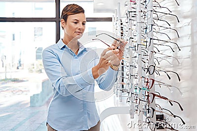 Say goodby to blur. Shot of a young woman buying a new pair of glasses at an optometrist store. Stock Photo