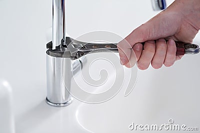 Say goodbye to water wastage. a person repairing a tap with a wrench. Stock Photo