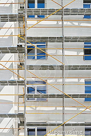 Scaffolding near a new house under construction, white wall and window, yellow pipe Stock Photo