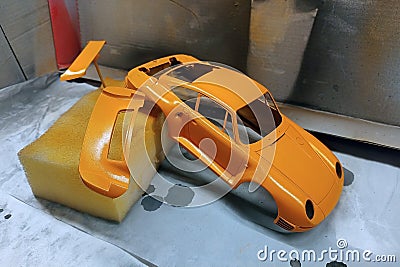 Scale model hobby. Paint the spoiler, trunk lid and toy body in a bright orange color Stock Photo
