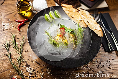 Scallop ceviche served in black bowl with liquid ice smoke Stock Photo