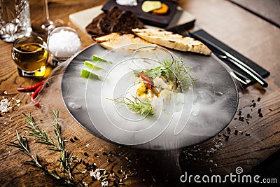 Scallop ceviche served in black bowl with liquid ice smoke Stock Photo