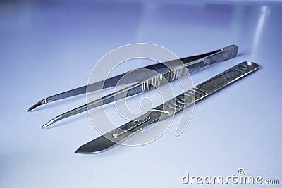 Scalpel and laboratory tweezers on a laboratory table. Labware Stock Photo