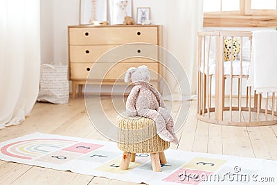 Scandinavian children`s room: a basket for toys, a plush rabbit sitting on a chair, a cradle for a baby bed. Modern interior of a Stock Photo