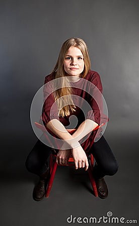 Scandinavian cute young girl sitting on a chair Stock Photo