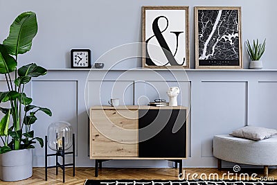 Scandinavian home interior of living room with two mock up poster frames, wooden commode, design black lamp, plants, decoration. Stock Photo