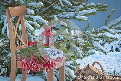 Scandinavian style wool mittens on Christmas plaid and chair near basketful of firewood Stock Photo