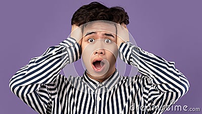 Scared asian man grimacing, screaming at purple studio Stock Photo