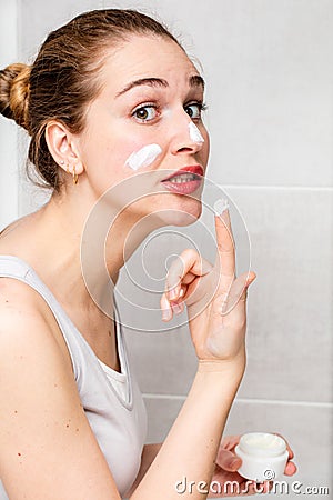 Scared beautiful girl applying dangerous face cream for risky routine Stock Photo