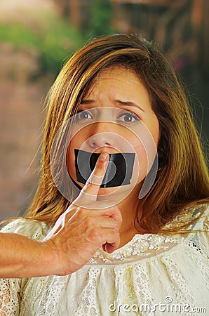 Scared beautiful young woman being silenced with tape on her mouth Stock Photo