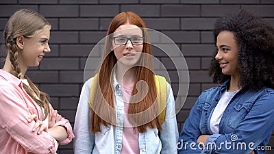 Scared bullying victim looking camera standing near insulting female students Stock Photo