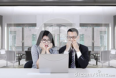 Scared business people looking at laptop Stock Photo
