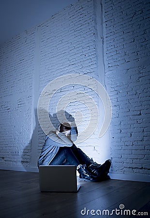 Scared female teenager with computer laptop suffering cyberbullying and harassment being online abused Stock Photo