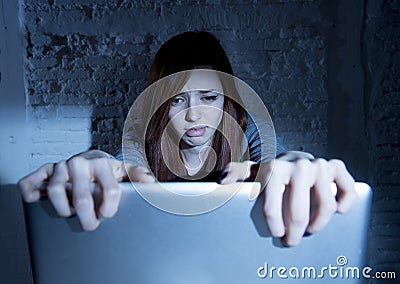 Scared female teenager with computer laptop suffering cyberbullying and harassment being online abused Stock Photo