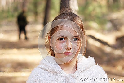 Scared girl alone in the forest, man on background Stock Photo