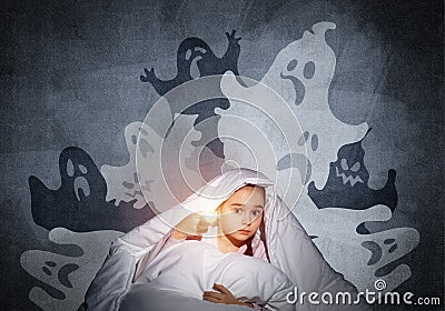 Scared girl with flashlight under blanket Stock Photo