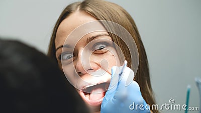 Scared girl treats teeth in a modern clinic. Cowardice and fear of the dentist. Stock Photo