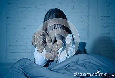 Scared little girl covering face with hands in fear in darkness at night Stock Photo