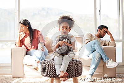 Scared little kid with afro sitting and holding teddy bear while parents fight. African American couple ignoring each Stock Photo