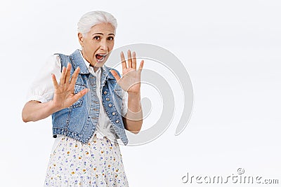 Scared speechless, shocked timid senior woman being victim of attack, trying protect herself with raised hands step Stock Photo