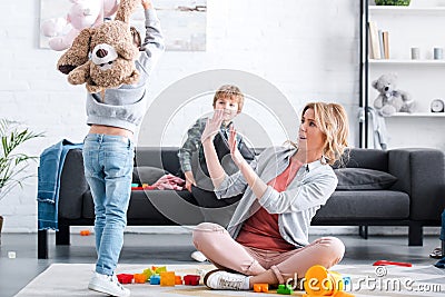 scared tired mother looking at naughty children playing Stock Photo