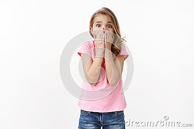 Scared troubled young cute blond little girl calling for help, panicking, feel frightened gasping shocked cover mouth Stock Photo