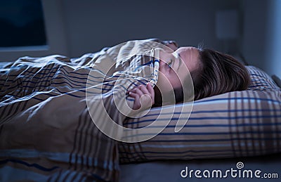 Scared woman hiding under blanket. Afraid of the dark. Unable to sleep after nightmare or bad dream. Stock Photo