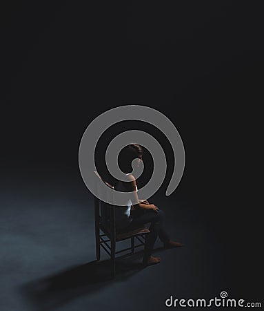 Scared woman sitting on the chair in the dark Stock Photo