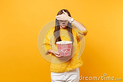 Scared young girl in 3d imax glasses covering face with palm, watching movie film, holding bucket of popcorn isolated on Stock Photo