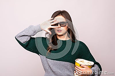 Scared young girl in 3d imax glasses covering face with palm, watching movie film, holding bucket of popcorn isolated on white Stock Photo