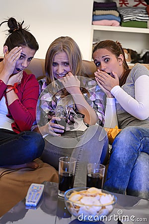 Scared girls watching horror movie on television Stock Photo