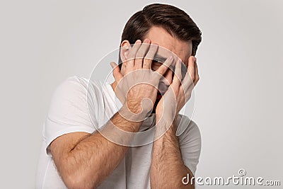Scared Caucasian man cover face peeping through fingers Stock Photo