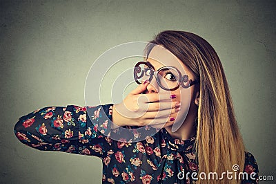 Scared young woman in glasses covering with hand her mouth Stock Photo