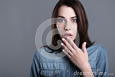 Scared young woman raising hand to her mouth Stock Photo