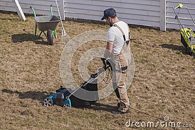 Scarifying lawn with scarifier, Man gardener scarifies the lawn and removal of old grass Stock Photo