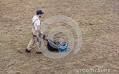 Scarifying lawn with scarifier, Man gardener scarifies the lawn and removal of old grass Stock Photo