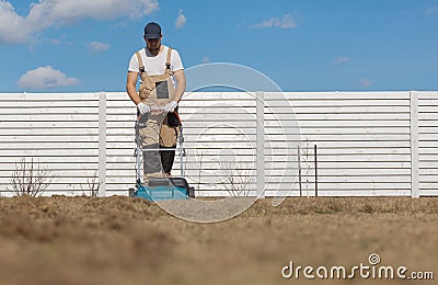 Scarifying lawn with scarifier, Man gardener scarifies the lawn and removal of old grass Stock Photo