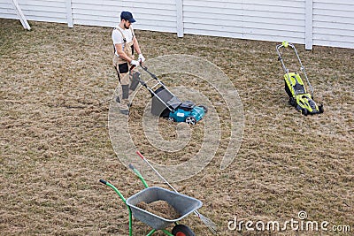 Scarifying lawn with scarifier, Man gardener scarifies the lawn and removal of old grass Stock Photo