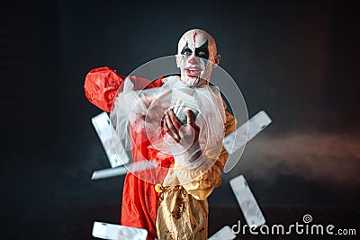 Bloody clown with crazy eyes holds fan of money Stock Photo