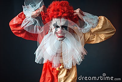 Scary bloody clown tears his hair, jerk in anger Stock Photo