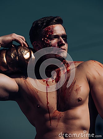 Scary and bloody muscular zombie man with pumpkin in outdoor. Day of The Dead. Halloween. Scary face man with horror Stock Photo