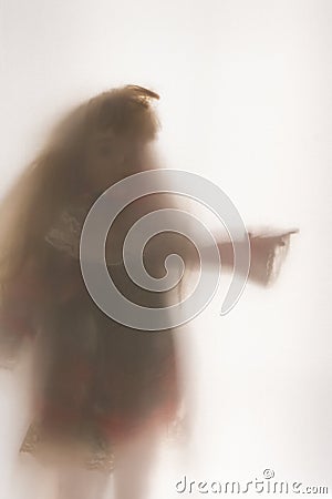 A scary edit of an old doll pointing, shot through a semi transparent material. Creating a textured, blurred, still life Stock Photo