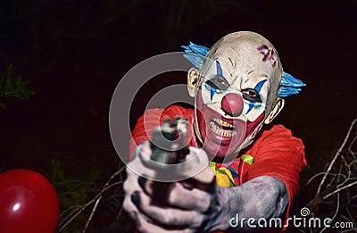 Scary evil clown with a gun Stock Photo