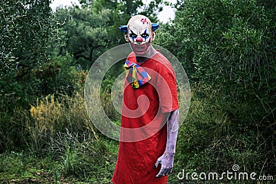 Scary evil clown in the woods Stock Photo