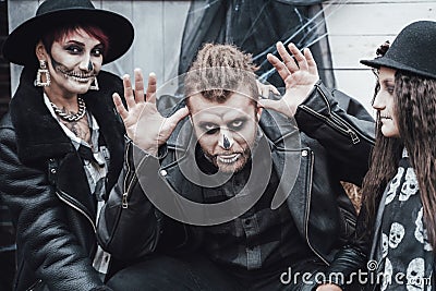 Scary family, mother, father, daughters celebrating halloween. Terrifying black skull half-face makeup and witch Stock Photo