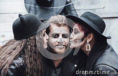 Scary family, mother, father, daughters celebrating halloween. Terrifying black skull half-face makeup and witch Stock Photo