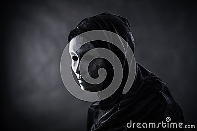 Scary figure with hooded cape in the dark Stock Photo