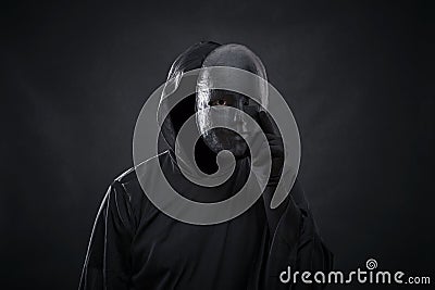 Scary figure in hooded cloak with mask in hand Stock Photo